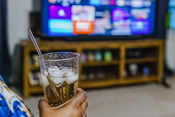 Woman Watches TV While Drinking Beverage With Metal Straw