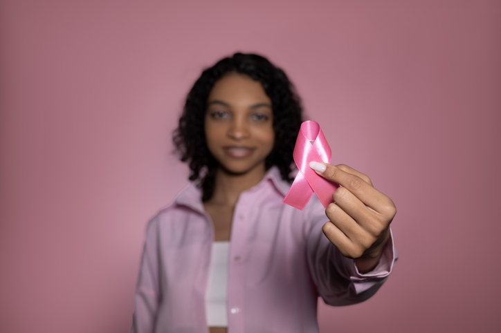 Breast cancer awareness concept.Smiling,cheerful girl holding pink ribbon