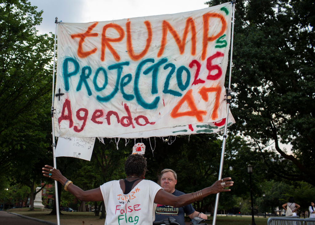 Activist Nadine Seiler holding a sign with Trump's Project...