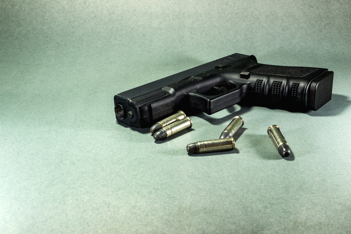 High Angle View Of Handgun And Bullets On Textured Table - gun violence