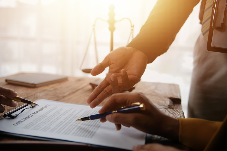 Business and lawyers discussing contract papers with brass scale on desk in office. Law, legal services, advice, justice and law concept picture with film grain effect