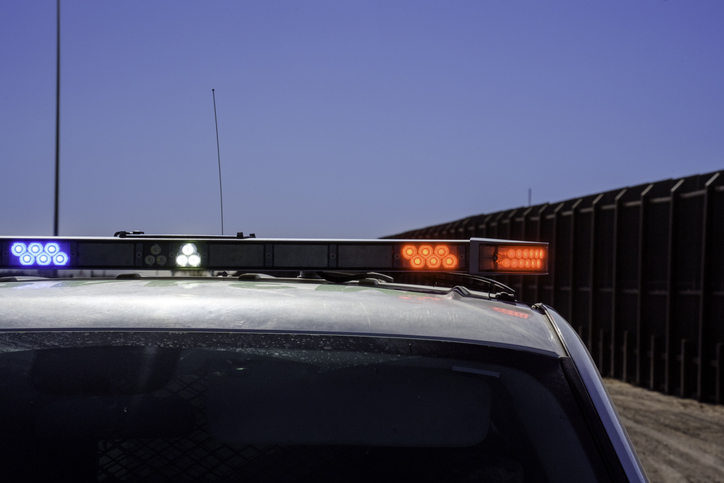 Border Patrol Vehicle with Police Lights On Sitting in Front of Border Barrier Wall at Santa Teresa Crossing Into Mexico