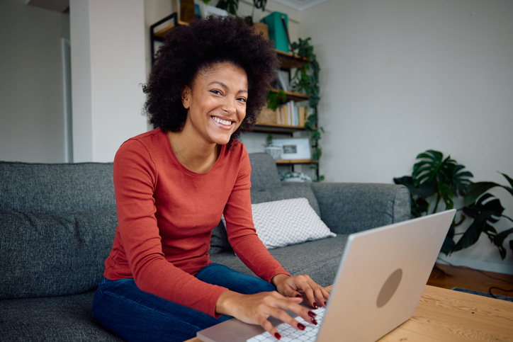 A photo of a mixed race woman using her computer to make notes