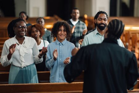 Congregation clapping and singing in church pew