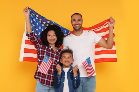 4th of July - Independence Day of USA. Happy family with American flags on yellow background