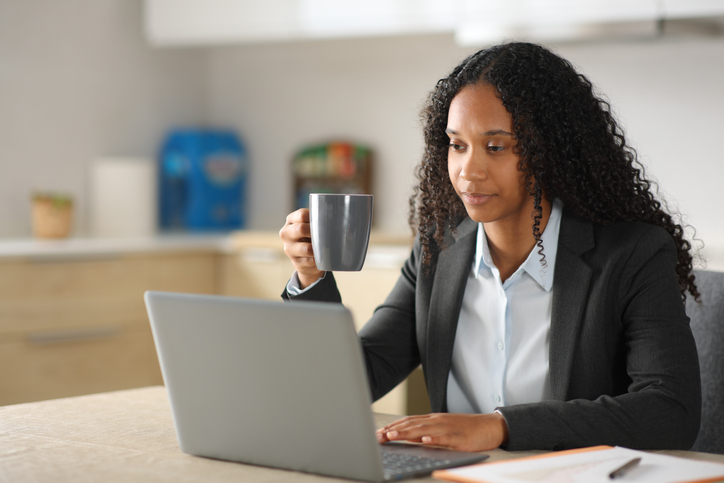 Black young executive using laptop working in the kitchen