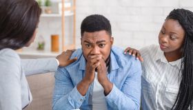Caring black wife and counselor supporting man during psychotherapy session