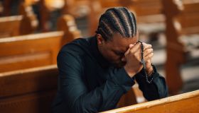 Young man praying with rosary in church pew