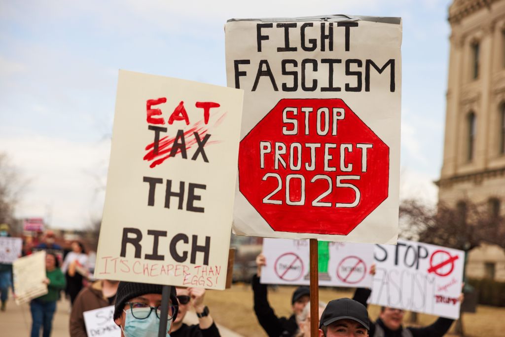A protester holds a sign reading "Fight Fascism Stop...