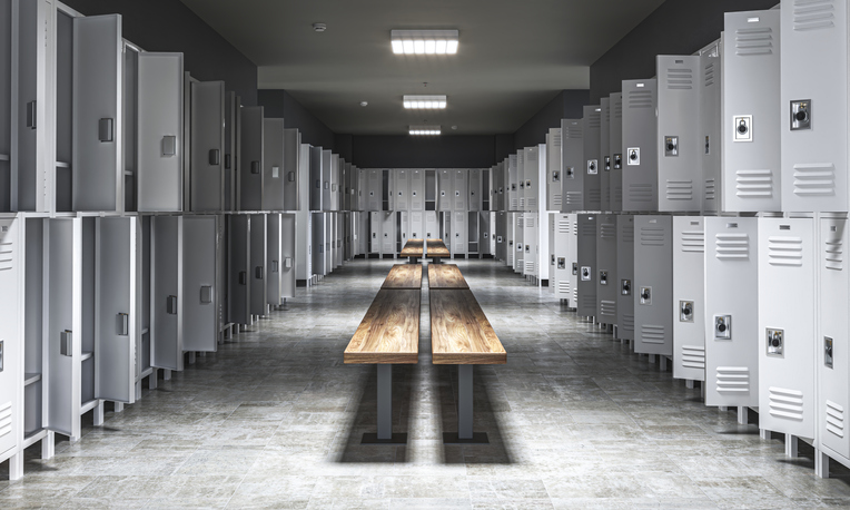 Empty school locker room with wooden benches and gray lockers
