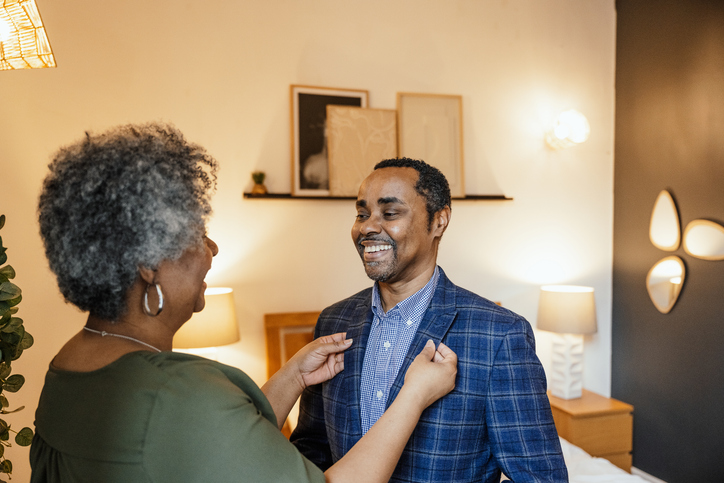 Mature woman of color dressing up her husband before going to work
