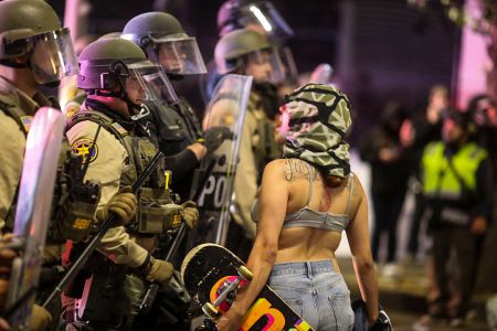 A demonstrator yells at Police officers in riot gear