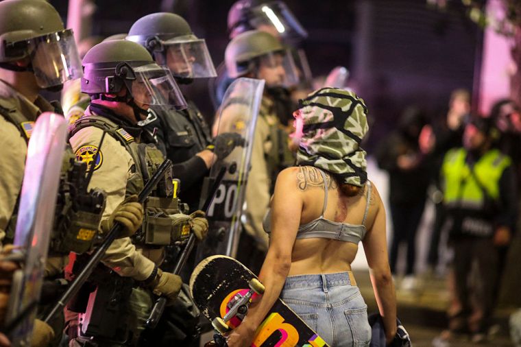 A demonstrator yells at Police officers in riot gear