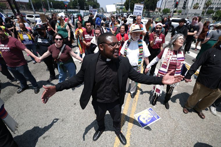 Religious leaders stand in a street outside the Metropolitan Detention center during a protests