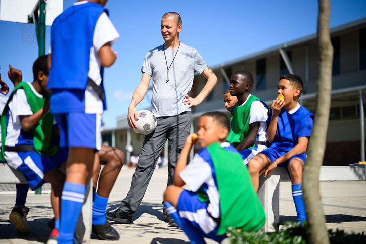 Low angle view of soccer coach mentoring school children after a practise match