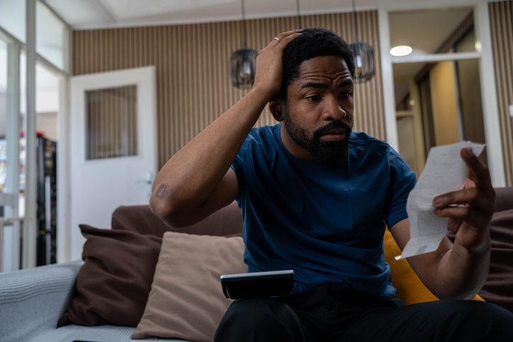 Young man feeling stressed calculating expenditures or taxes