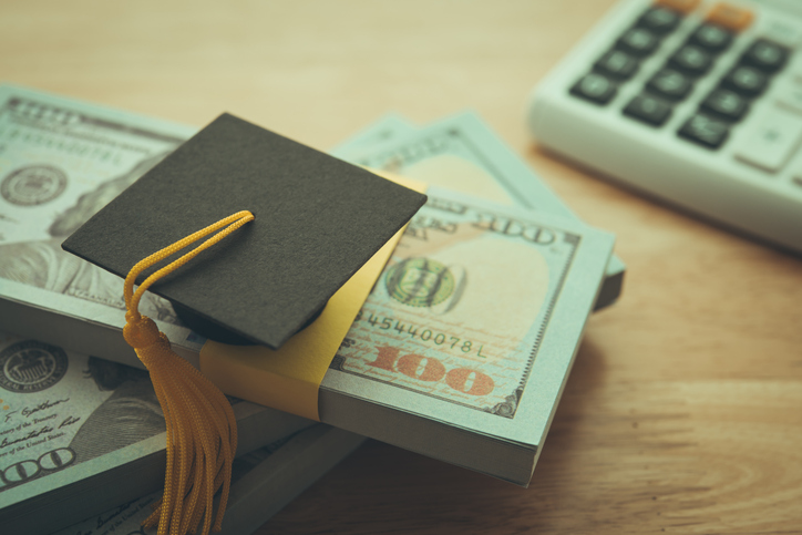 Graduation cap university on stack US dollar banknote, calculator.