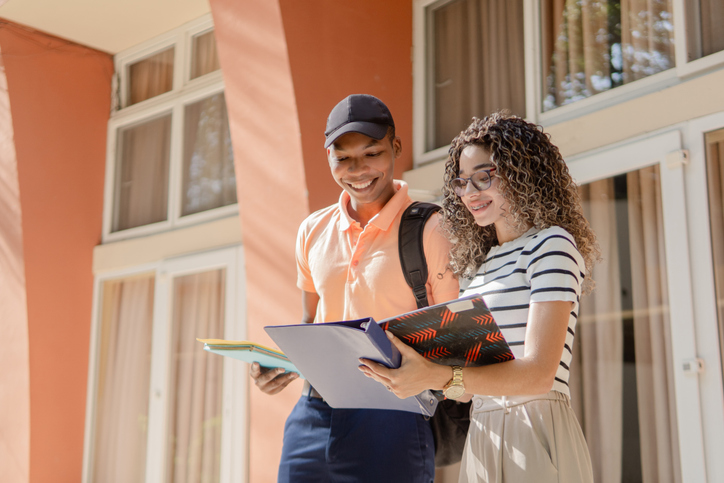 Two smiling university students reviewing notes outdoors