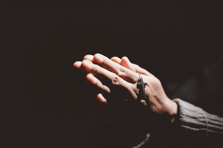 Person holding hands together in prayer gesture, symbolizing hope, faith, meditation, spirituality, trust, belief, peace, devotion, inner strength and resilience during hard times.
