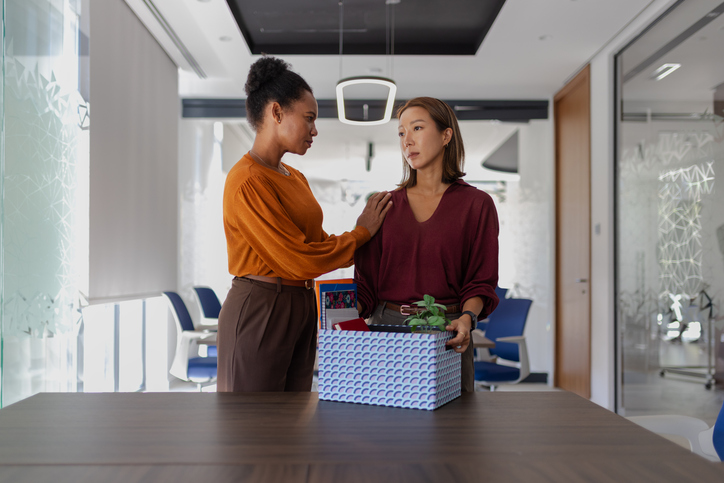 Supportive coworker comforting departing employee after job loss