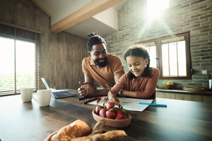 Happy black father and daughter coloring at home.