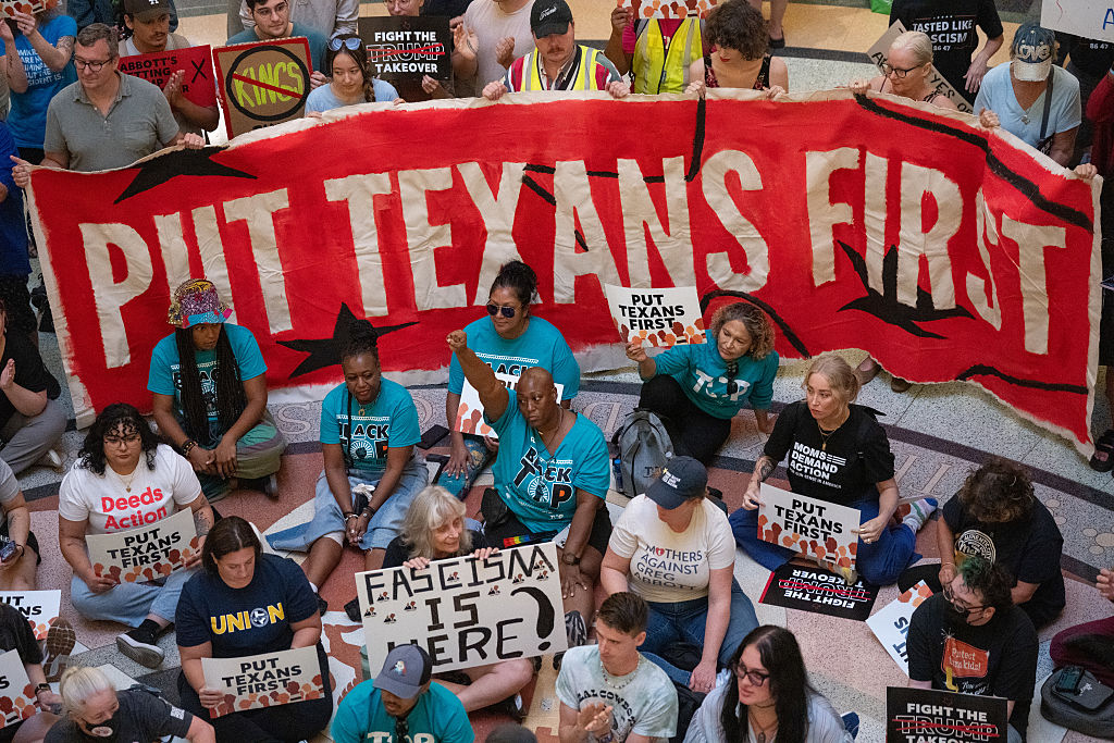 LaToya Forbins raises a fist as activists protest against mid-decade redistricting...