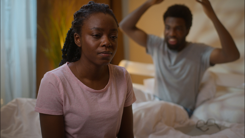 African American couple quarrel family ethnic angry furious boyfriend screaming shouting depressed girlfriend sitting bed fight breakup crisis marriage dating divorce argument at home bedroom evening