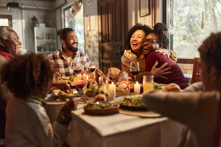 Happy black mother and daughter embracing during Thanksgiving lunch at home.