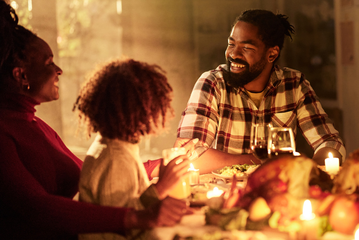 Happy black family enjoying in Thanksgiving meal at dining table.
