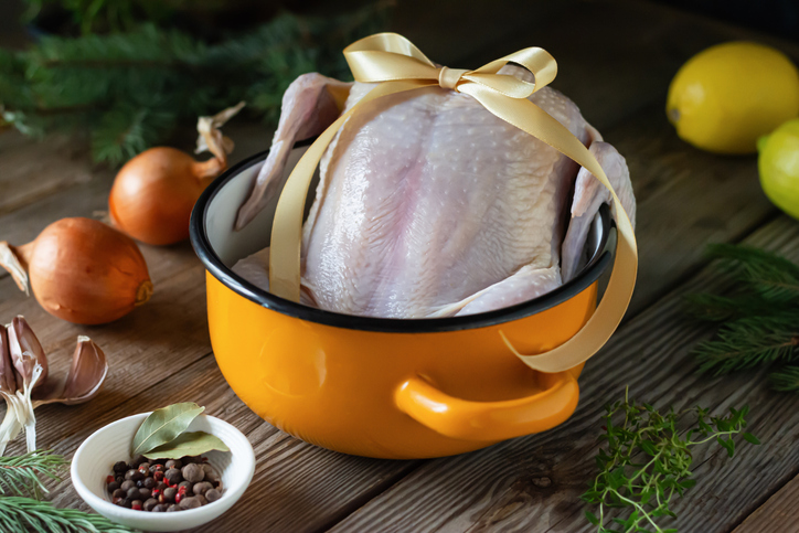 Raw chicken in a pot for broth, roasting on a wooden background