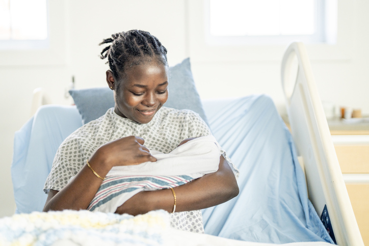 Young Black Mother Cradling Newborn Baby in Hospital Bed, Tender Moment of New Motherhood