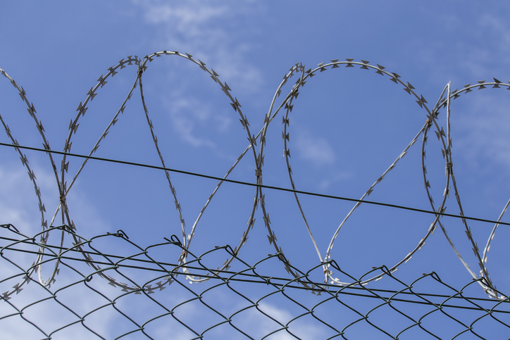 Chain link fence with barbed wire under blue sky