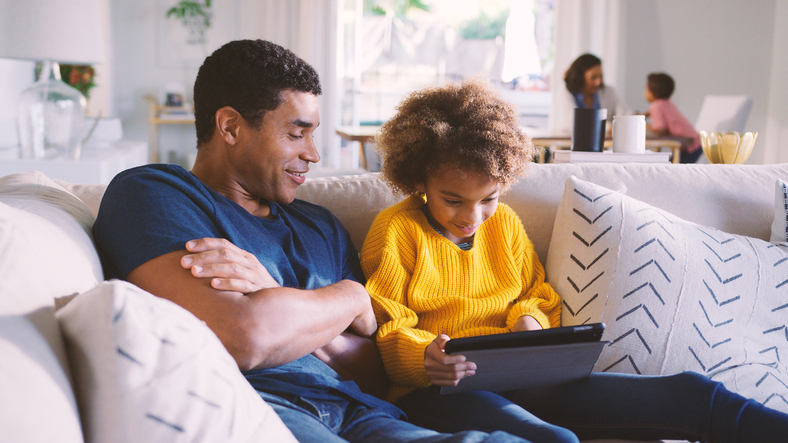 Family At Home With Father And Daughter Using Digital Tablet In Foreground