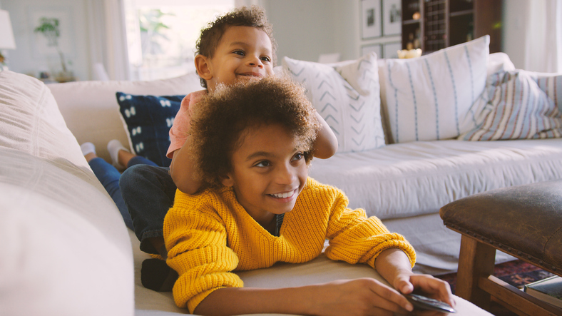 Brother And Sister Lying On Sofa At Home Watching TV Together