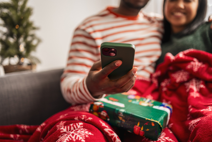Couple using smartphone during cozy christmas holiday