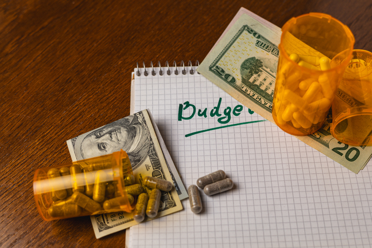 Budget planning with money and medicine on a notepad at home desk