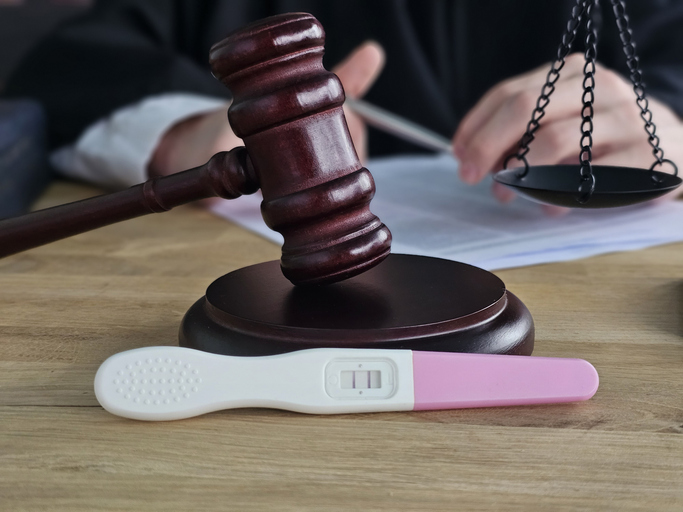 Courtroom setting with gavel and a pregnancy test, symbolizing legal issues related to family matters and parental rights concept