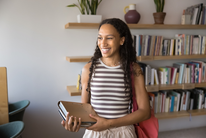Cheerful beautiful African American female student standing in public library