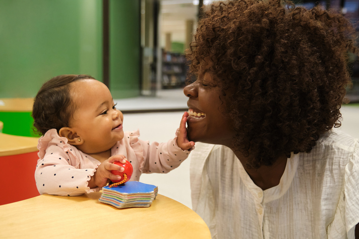 Baby girl playing and touching her mother's face, having fun together