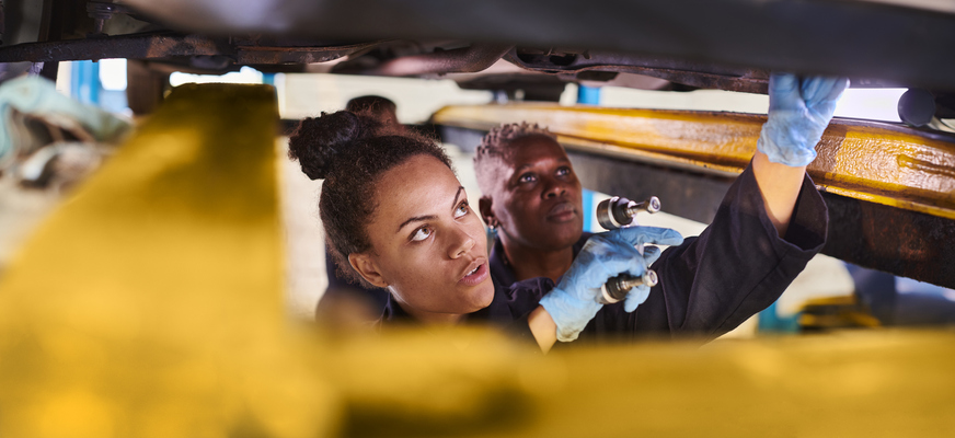 female apprentice mechanic underneath a car