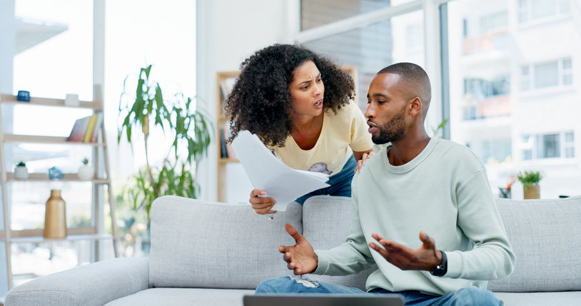 Fight, finance and couple with paperwork on sofa with conflict for expenses, debt and laptop. Marriage, home and African man and woman with documents for financial review, payment fail or bankruptcy