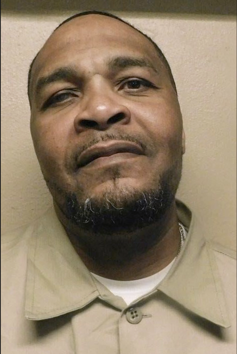 A close-up portrait of a middle-aged Black man with a beard, looking directly at the camera with a serious expression.