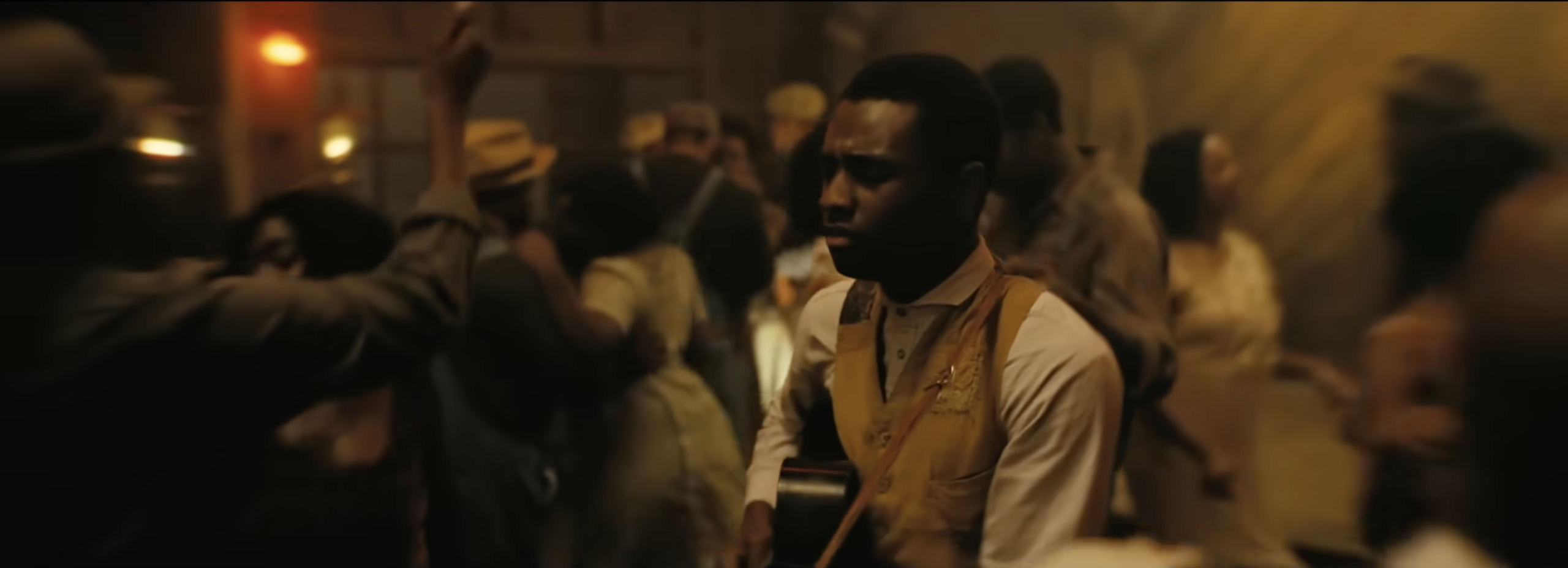 A group of people gathered in a dimly lit setting, with one person in the center wearing a yellow vest.
