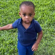 Young child in blue shirt standing in grass
