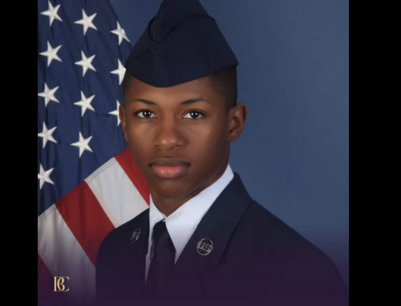 A young man in military uniform standing in front of an American flag.