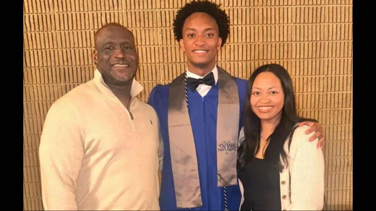Three people posing for a photo: a smiling older man, a younger man in a graduation gown, and a smiling woman.