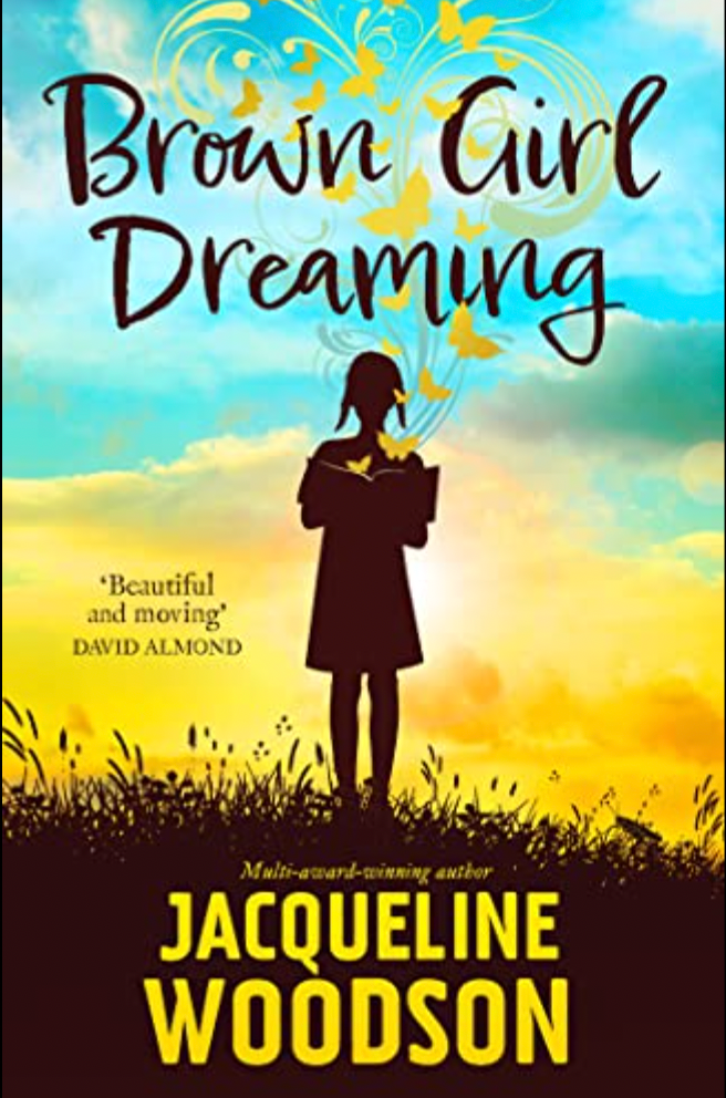 Silhouette of a person standing in a field, surrounded by butterflies and a colorful sky. Text reads "Brown Girl Dreaming" by Jacqueline Woodson.