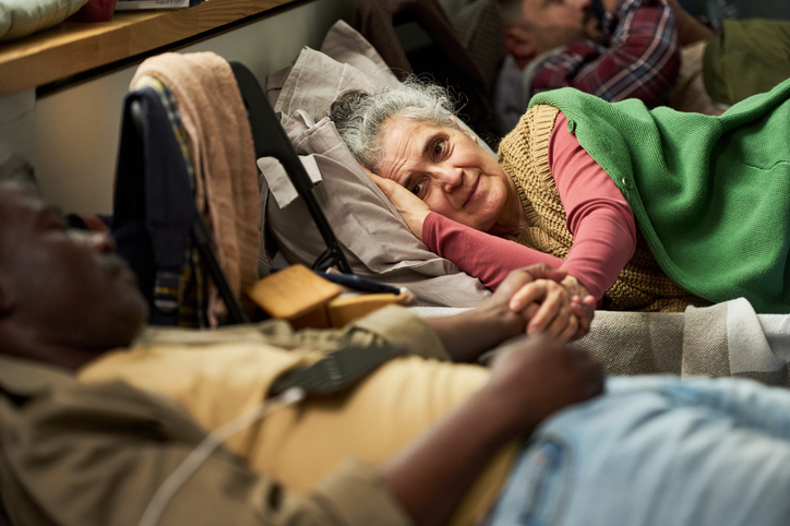 Senior Woman Comforting Black Man in Care Facility Bedside Visit
