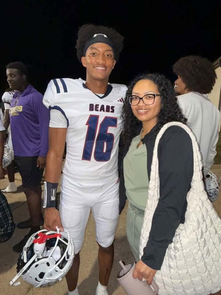 A smiling young man wearing a white football jersey with the number 16 and the word "Bears" stands next to a young woman wearing glasses.