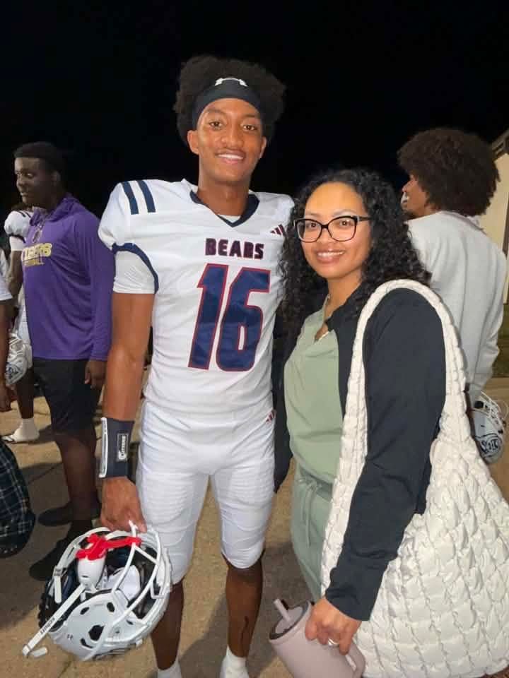 A smiling young man wearing a white football jersey with the number 16 and the word "Bears" stands next to a young woman wearing glasses.